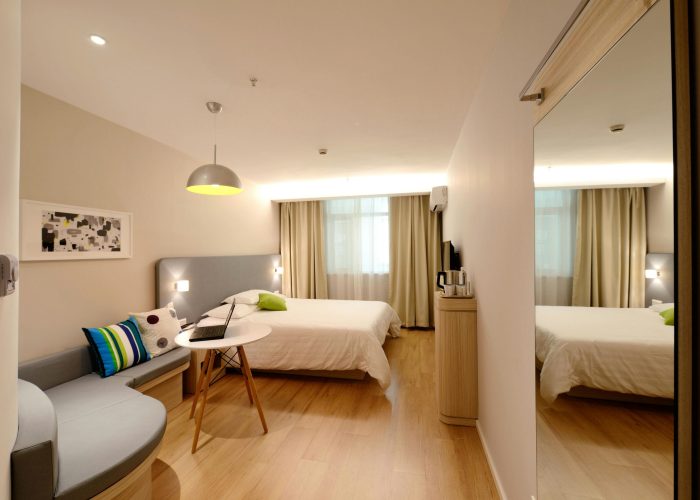 Spacious modern hotel room featuring cozy decor and neutral tones with natural light.